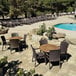 A Grosfillex Havana bronze armchair and table on an outdoor patio by a pool.