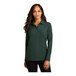 A woman wearing a dark green Port Authority long sleeve polo shirt.