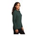 A woman wearing a dark green Port Authority long sleeve polo shirt.