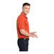A man wearing a deep orange Sport-Tek polo shirt.
