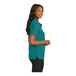 A woman wearing a teal Port Authority polo shirt.