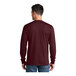 A man wearing a maroon Port & Company long sleeve t-shirt.