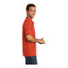 A man wearing a small orange Port & Company polo shirt.