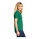 A woman wearing a kelly green Sport-Tek short sleeve polo shirt.