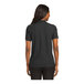 A woman wearing a black Port Authority polo shirt.