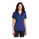 A woman wearing a Port Authority royal blue silk touch polo shirt.