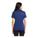 A woman wearing a Port Authority Royal Blue Silk Touch polo shirt.