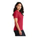 A woman wearing a Port Authority rich red polo shirt.