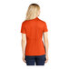 A woman wearing a deep orange Sport-Tek short sleeve polo shirt.