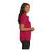 A woman wearing a red Port Authority polo shirt.