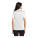 A woman wearing a white Port Authority silk touch polo shirt.