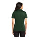 A woman wearing a dark green Port Authority silk touch polo shirt.