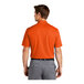 A man wearing a Nike brilliant orange polo shirt.