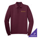 A Port Authority burgundy long sleeve polo shirt on a counter with gold embroidery.