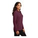 A woman wearing a burgundy Port Authority long sleeve polo shirt.