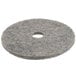 A close-up of a grey circular Scrubble floor pad with a hole in the center.