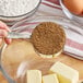 A measuring spoon of Wholesome Sweeteners Organic Light Brown Sugar being poured into a bowl.