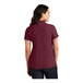 A woman wearing a Port Authority women's maroon short sleeve polo shirt.