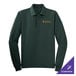 A dark green long sleeve Port Authority polo shirt on a counter with gold embroidery.