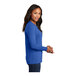 A woman wearing a royal blue Port & Company long sleeve t-shirt.