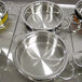 A group of Bon Chef Classic Country French red and silver pots on a metal surface.