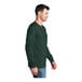 A man wearing a dark green Port & Company long sleeve t-shirt.