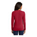 A woman wearing a red Port & Company long sleeve t-shirt.