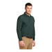 A man wearing a dark green Port Authority® long sleeve polo shirt.