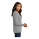 A woman wearing a Port & Company athletic heather long sleeve T-shirt.