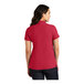A woman wearing a rich red Port Authority polo shirt.