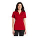 A woman wearing a red Port Authority short sleeve polo shirt.