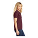 A woman wearing a maroon Sport-Tek short sleeve polo shirt.