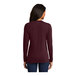 A woman wearing a maroon Port & Company long sleeve T-shirt.