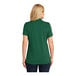 A woman wearing a deep forest green Port Authority Dry Zone short sleeve polo shirt.