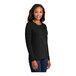 A woman wearing a Port & Company jet black long sleeve t-shirt.