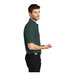 A man wearing a Port Authority dark green silk touch pique polo shirt.