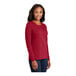 A woman wearing a red Port & Company long sleeve T-shirt.