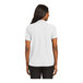 A woman wearing a white Port Authority silk touch polo shirt.