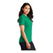 A woman wearing a bright kelly green Port Authority polo shirt.