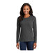 A woman wearing a dark heather grey Port & Company long sleeve t-shirt.