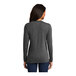 A woman wearing a dark heather grey Port & Company long sleeve t-shirt.