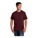 A man smiling and wearing a Port & Company athletic maroon short sleeve t-shirt.