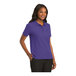 A woman wearing a purple Port Authority silk touch polo shirt.
