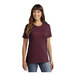 A woman wearing a Port & Company maroon short sleeve t-shirt.