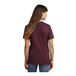 A woman wearing a Port & Company maroon T-shirt.