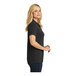 A woman wearing a black Port Authority Dry Zone polo shirt.