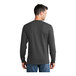 A man wearing a dark heather grey Port & Company long sleeve t-shirt.