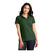 A woman wearing a Port Authority deep forest green short sleeve polo shirt.