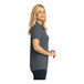 A woman wearing a graphite Port Authority Dry Zone short sleeve polo shirt.