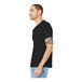 A man wearing a black Bella + Canvas customizable t-shirt.